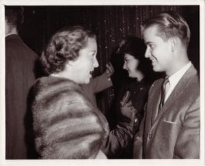 A vintage photo capturing a man conversing with a woman.