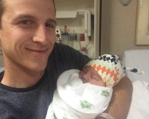 A man with cerebral palsy of Arizona holding a baby during home and community based services in a hospital bed.