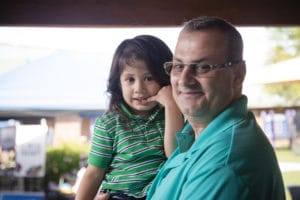 A man holding a young boy at a home and community based services event.