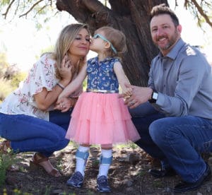 A family is posing for a picture with a little girl in a pink dress at Home and Community Based Services.