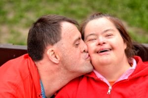 A couple enjoying a loving moment on a bench.