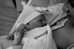 A woman holding a baby in a pediatric therapy session at an early learning center.