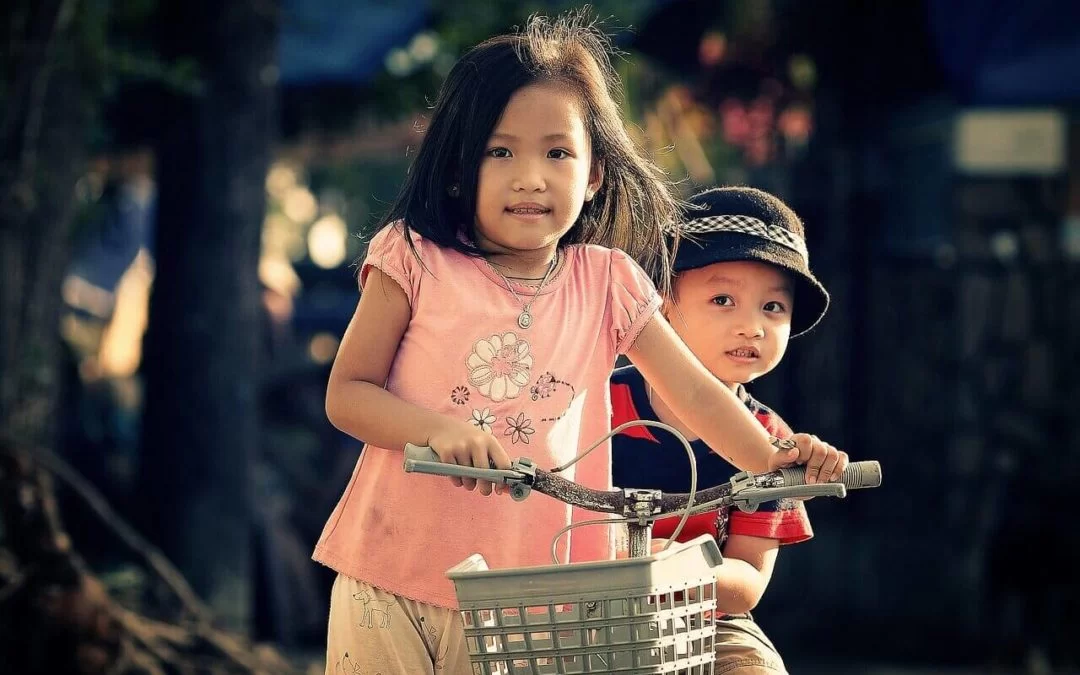 A boy and a girl standing next to a bicycle at the Cerebral Palsy of Arizona's Early Learning Center.