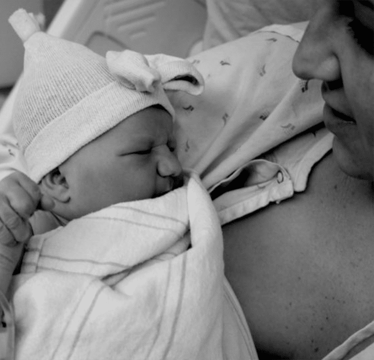 A woman is holding a baby in a hospital bed, possibly receiving day treatment for adults or pediatric therapy.