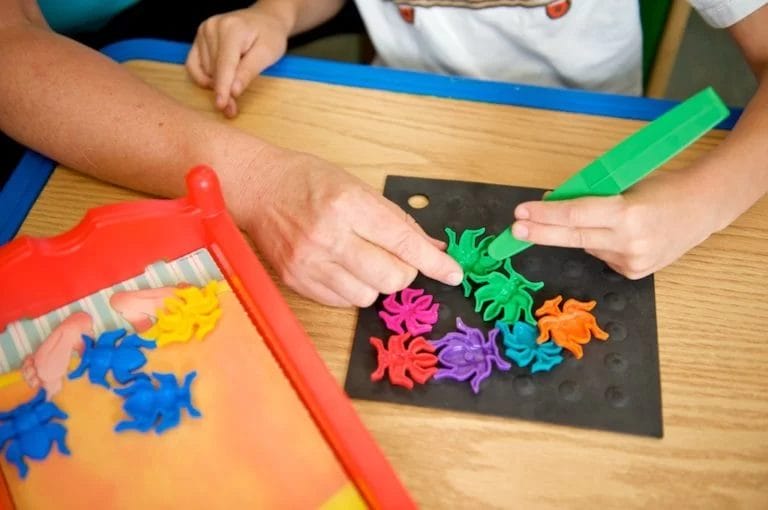 A child with cerebral palsy of Arizona is playing with a set of colorful shapes at a pediatric therapy and early learning center.