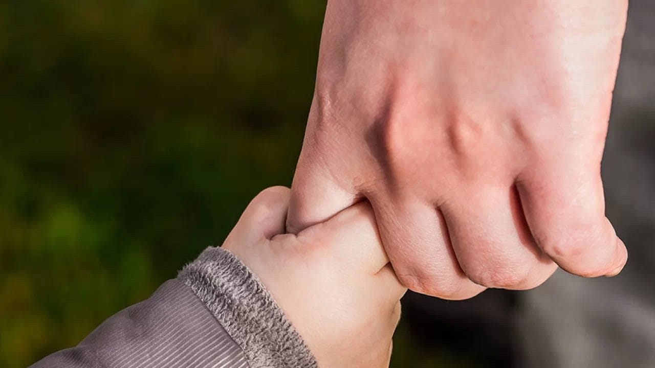 A man guiding a child's hand at an early learning center.