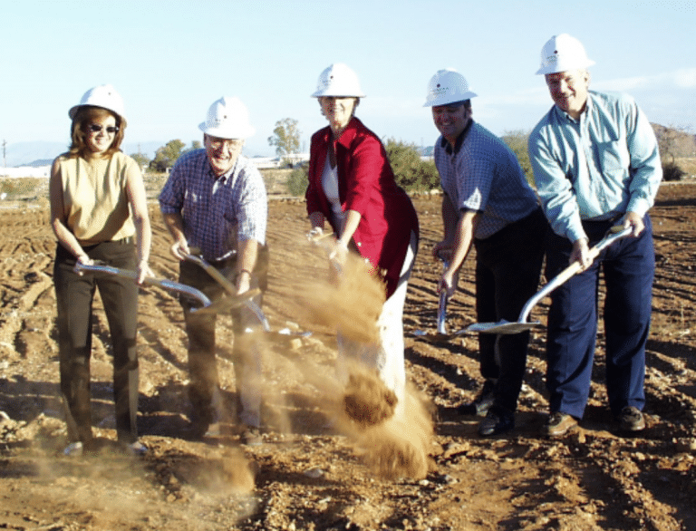 A group of adults from the Cerebral Palsy of Arizona engaging in day treatment, holding shovels in a dirt field at an early learning center.