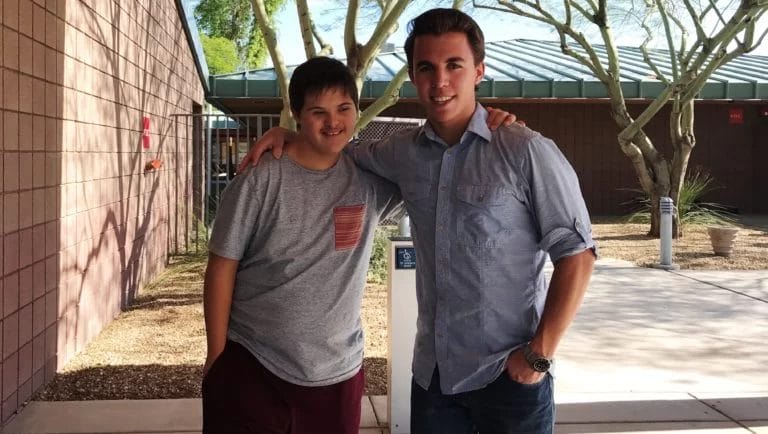 Two boys with cerebral palsy of Arizona posing for a picture in front of a building.