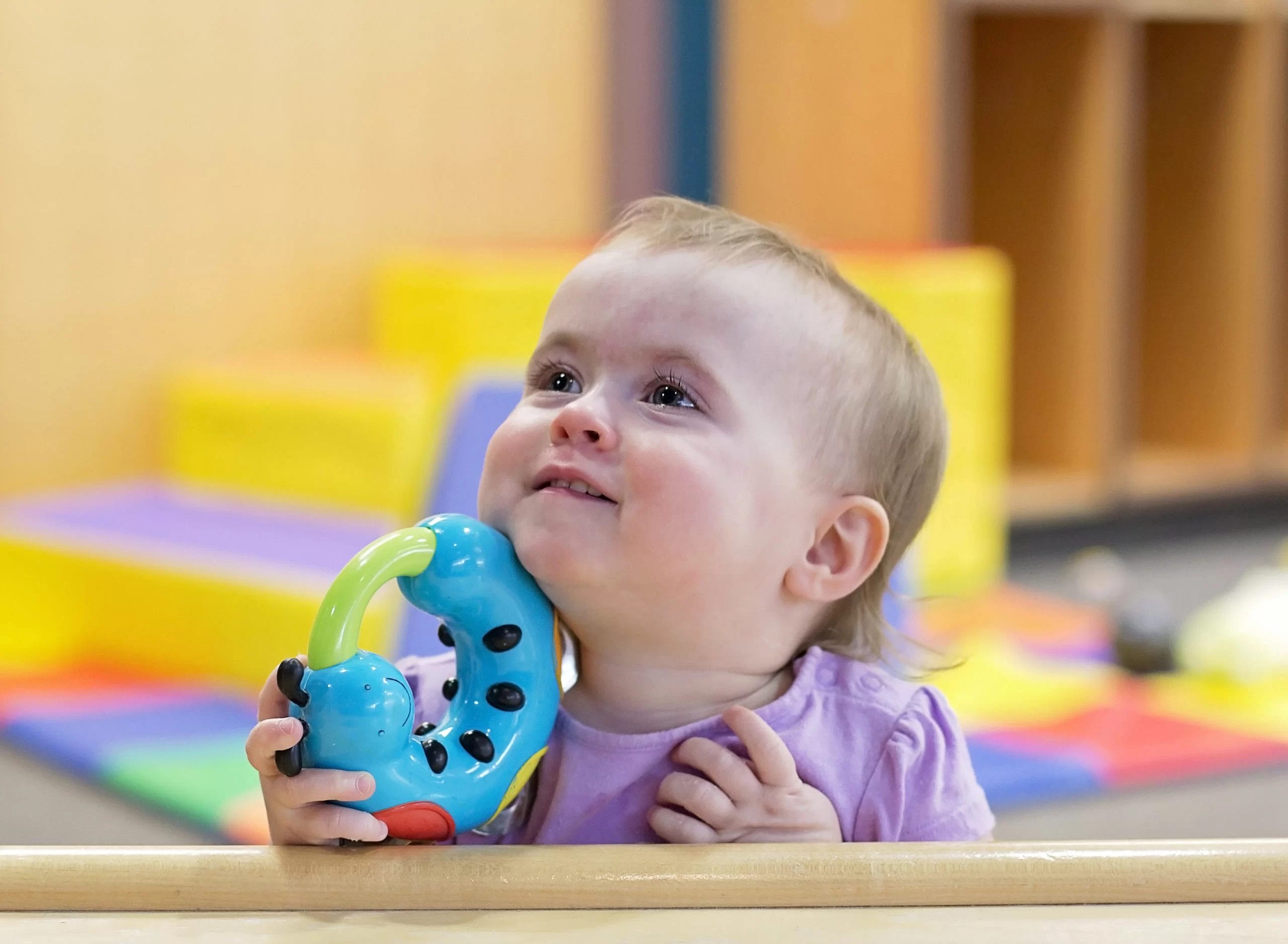 A baby with cerebral palsy playing with a toy in an early learning center.