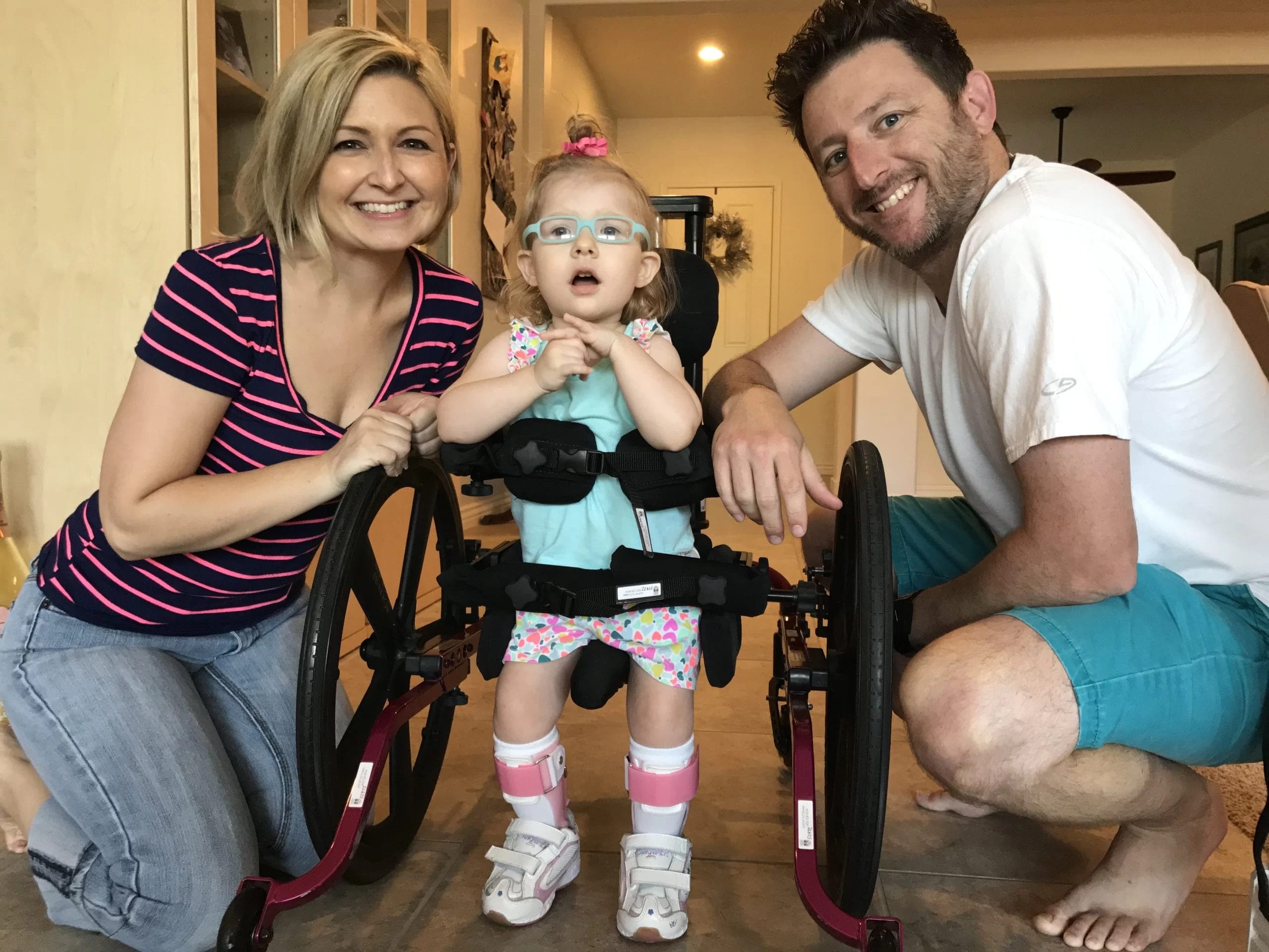 A little girl with cerebral palsy of Arizona poses for a photo with a man and woman, emphasizing the importance of pediatric therapy in home and community based services.