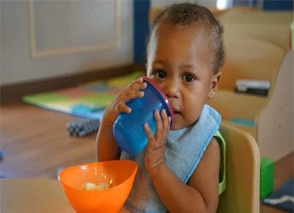 A baby with cerebral palsy of Arizona drinking from a bowl in an early learning center.