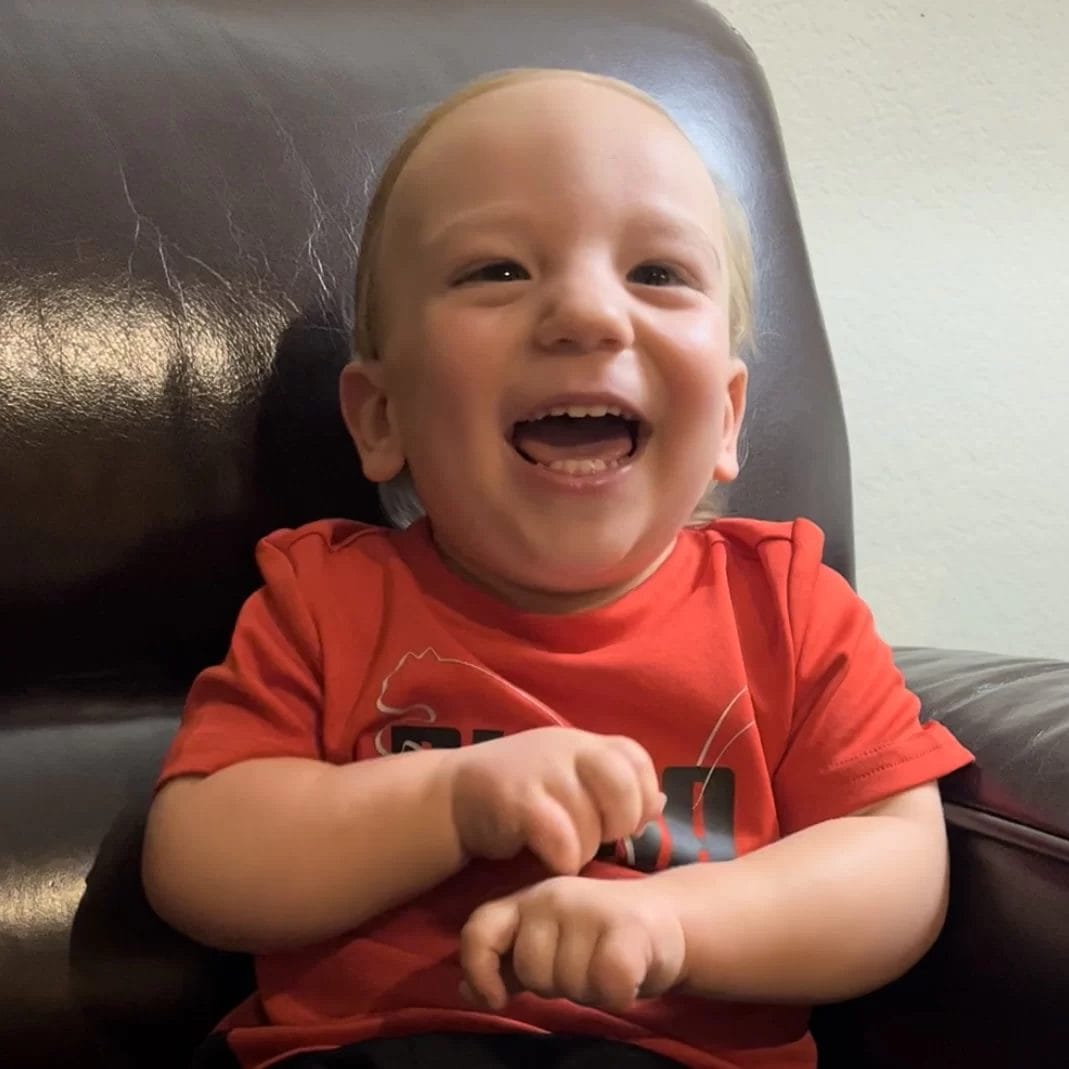 A baby with cerebral palsy of Arizona is sitting in a chair at an early learning center and laughing.