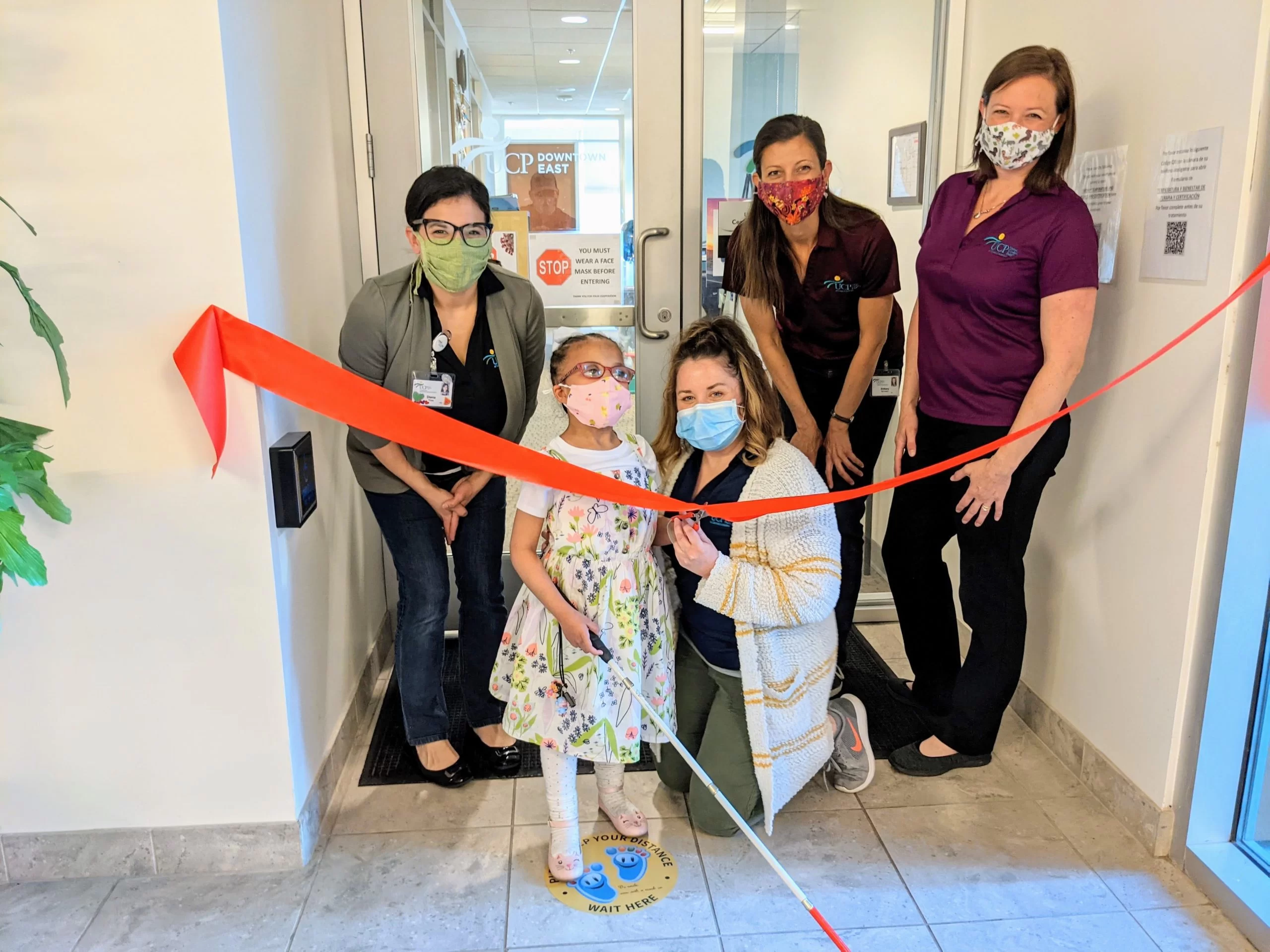 A group of people from the home and community based services program stand in front of a door at the early learning center for cerebral palsy of Arizona.