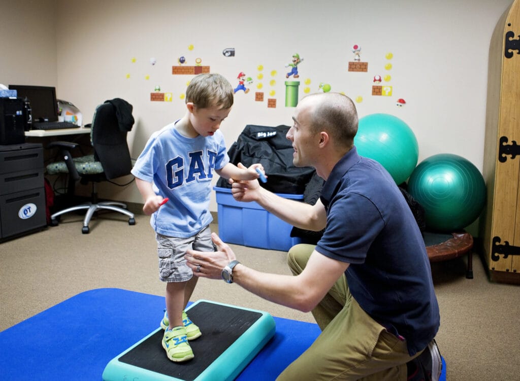 A young boy with cerebral palsy is being assisted by a pediatric therapist at the Early Learning Center in Arizona.