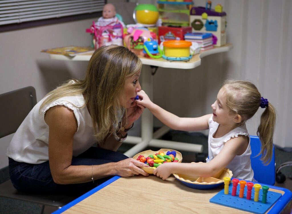 A little girl with cerebral palsy being fed by a woman at the Early Learning Center in Arizona.