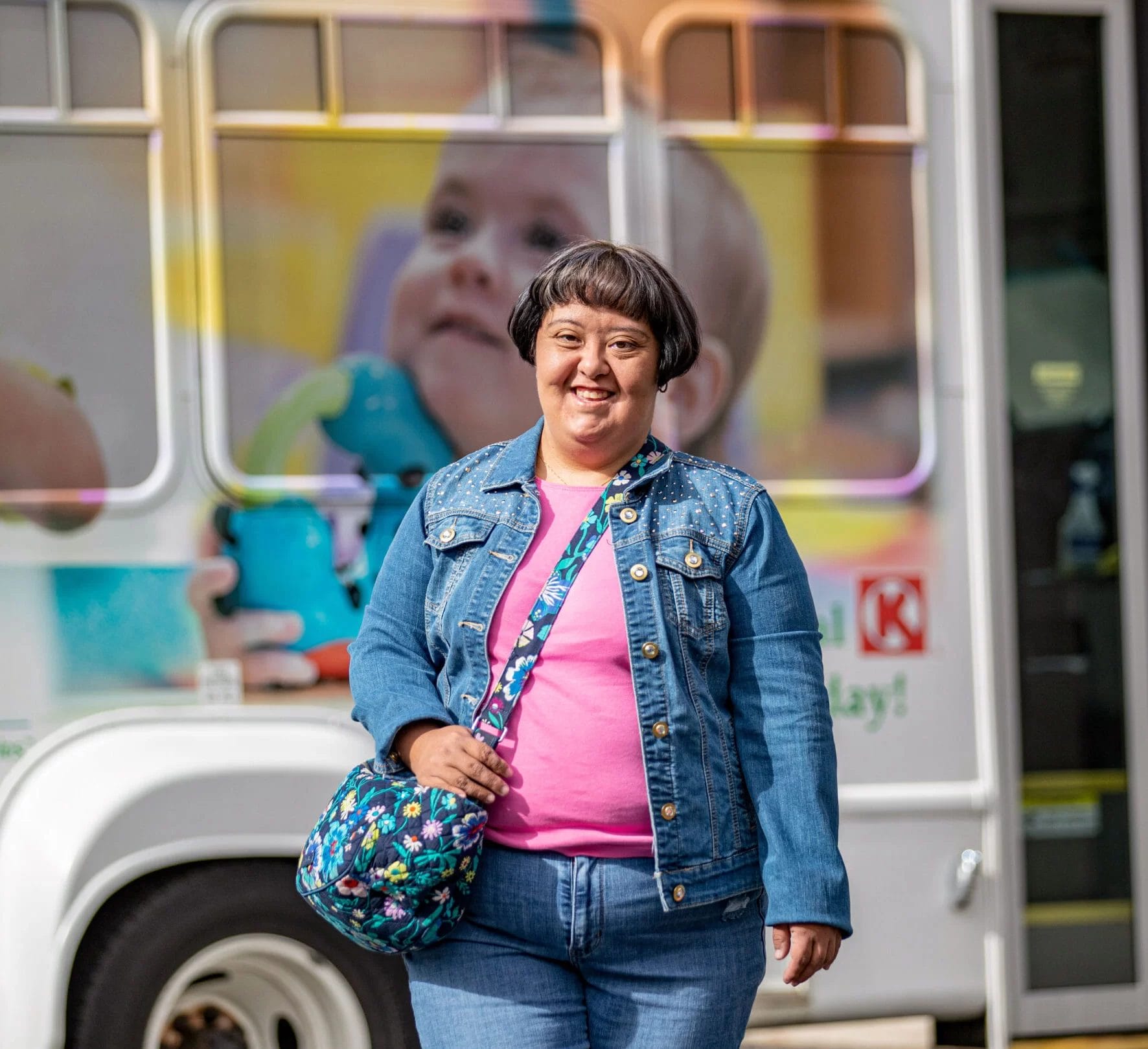 A woman with cerebral palsy standing in front of a bus, potentially accessing home and community based services or pediatric therapy.